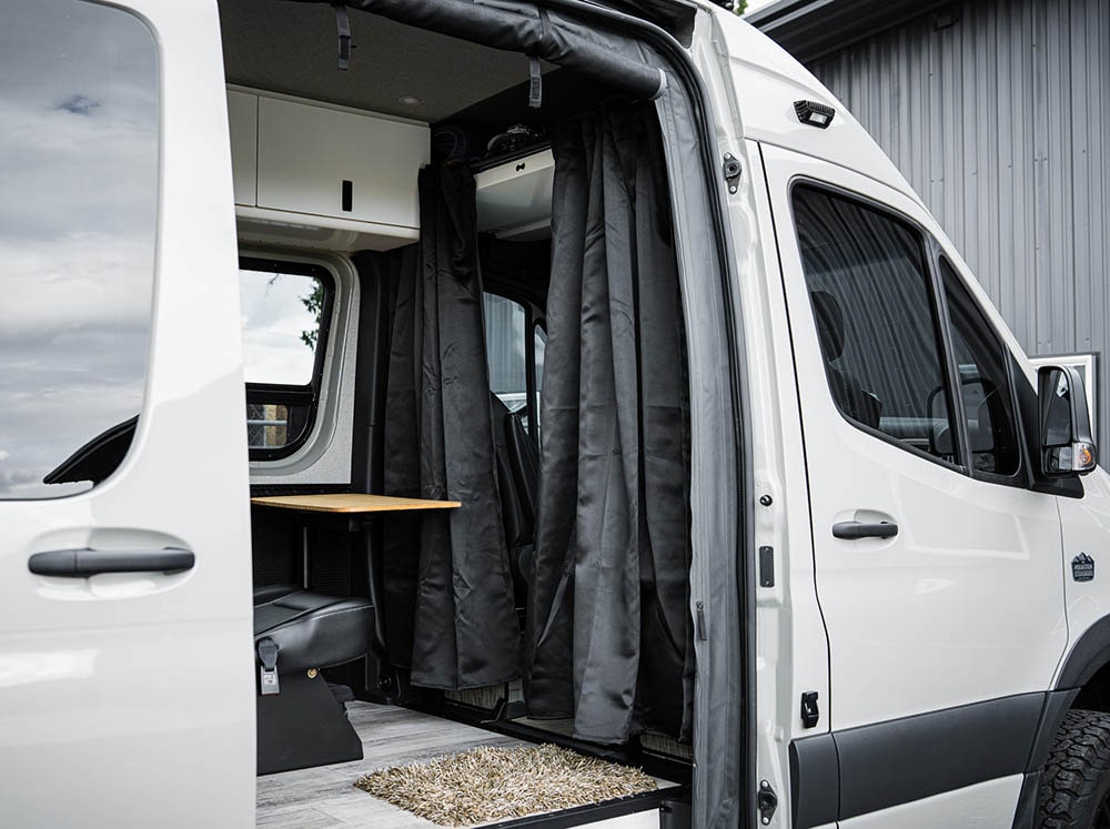 Blackout curtain hanging from the Sprinter headliner shelf curtain rod