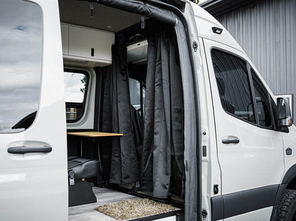 Blackout curtain hanging from the Sprinter headliner shelf curtain rod